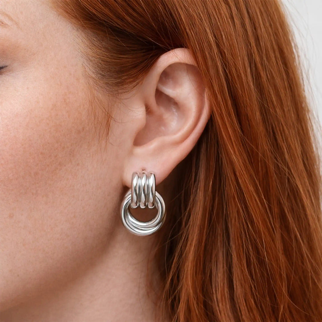 Riva Sculptural Knot Earrings silver on model ear — Tamola Jewellery
